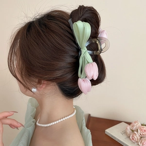 Detail view of a pink tulip ribbon hair claw clip worn on a low bun hairstyle