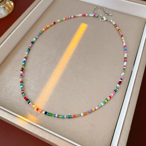 Detailed view of colorful glass seed bead necklace in a tray with warm natural sunlight