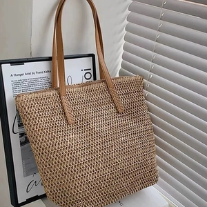 Detailed close-up of straw woven tote bag texture with brown leather strap detail