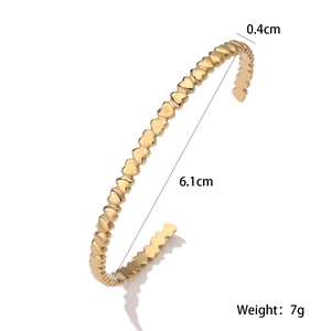 Detail showing 0.4cm width and 6.1cm diameter of this 18K gold heart pattern cuff bracelet