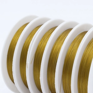 Macro shot of golden beading wire on white spools for DIY jewelry making material
