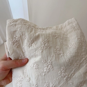Detail of floral embroidery on a white cotton canvas bag with a side brand woven label