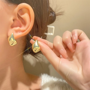 Minimalist gold teardrop earrings in high-polish finish shown worn on ear
