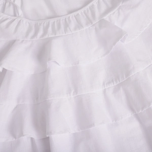 Close-up of white multi-layered ruffled tiers and pleated texture on a summer dress