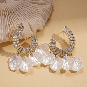 Détail de boucles d'oreilles dorées en C avec cristaux brillants et breloques en nacre