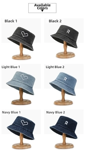Close-up of washed denim bucket hats with heart embroidery on wooden display stands