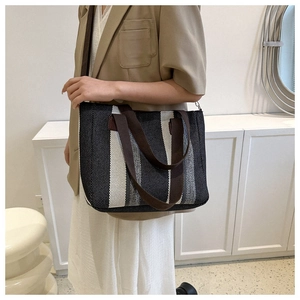 Detailed close-up showing woven vertical stripes texture and leather straps of the tote bag
