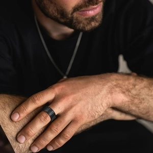 Men's 10mm wide black titanium steel ring with textured matte finish on a male finger