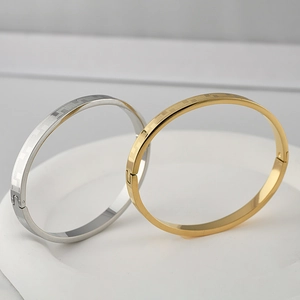Close-up of gold and silver steel bangles featuring geometric grid patterns and locks