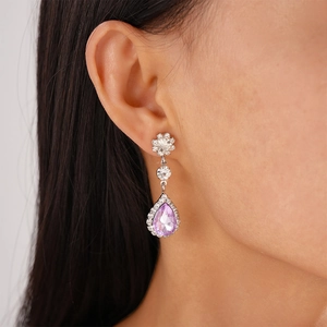 Close-up of elegant purple teardrop halo earrings with silver finish on model