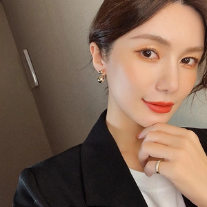 Close-up of minimalist golden double ball earrings and crystal ring on a model