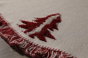 Detail of knitted 48-inch Christmas tree skirt with red fringe and 3D cedar tree patterns