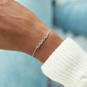 Bracelet vague en argent sterling S925 avec pierres bleues porté au poignet d'une femme