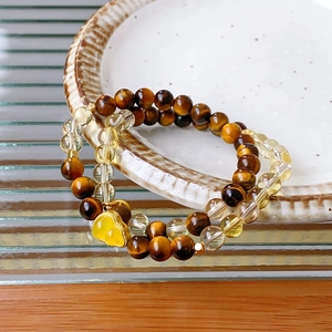 Close-up of double-layer beaded bracelet with tiger eye stones and yellow gourd charm