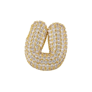 Macro detail of golden bubble letter U pendant with shimmering pavé zircon stones