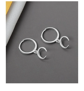 Close-up of polished silver crescent moon drop earrings with minimalist hoop detail