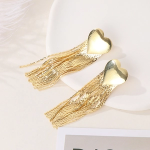 Detail of gold heart tassel earrings with sleek metallic finish on elegant white tray