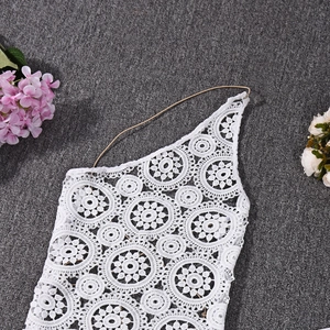Dettaglio flat lay di un crop top in pizzo all'uncinetto bianco su fondo grigio