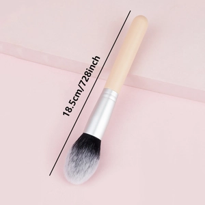Single wooden handle powder brush with gradient bristles on a pink geometric backdrop