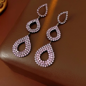 Macro detail of triple teardrop earrings featuring purple rhinestones on leather
