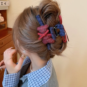 Detail of a navy and red plaid teddy bear hair claw clip with bow on a woman hair