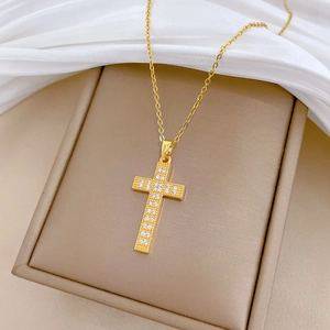 Macro detail of a golden cross pendant necklace with sparkling pavé zircons on silk