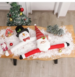 Plush Santa Claus and Snowman Christmas tree toppers on snowy wooden table background.