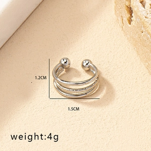 Detailed view of silver non-piercing nose ring and lip clip on a textured stone background