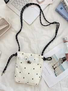 Floral embroidered canvas crossbody bag with woven strap on a lifestyle desk background