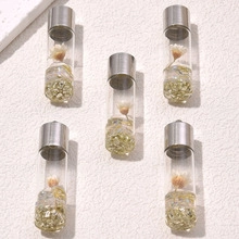 Detailed view of glass tube pendants with dried flowers and natural crushed stones