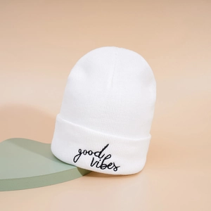 White knitted beanie with Good Vibes embroidery on a minimalist aesthetic background