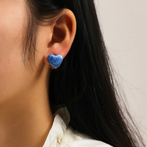 Gros plan de boucles d'oreilles cœur en émail marbré bleu avec placage d'or