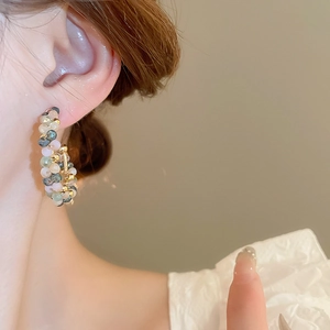 Close-up of elegant C-shaped earrings with colorful crystal beads on a female model