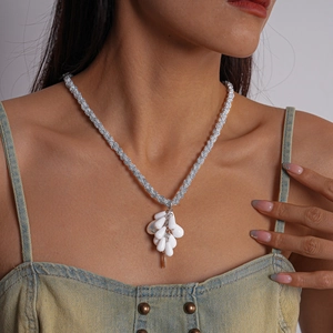 Close-up of a silver braided chain necklace with white teardrop pendants on a model