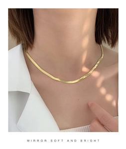 Macro shot of mirror-like soft texture on gold flat snake bone choker chain necklace