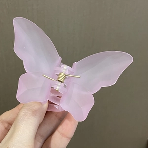 Primer plano de la pinza para el cabello mariposa rosa translúcida con muelle metálico