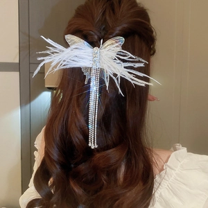 Detail view of white mesh bow hair clip with rhinestone tassels and wing accents