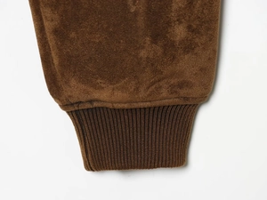 Détail du poignet d'une veste en daim marron foncé avec texture en maille côtelée souple