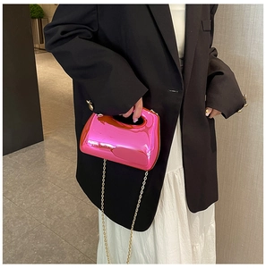 Close-up of bright pink acrylic crossbody bag with gold chain strap on black blazer