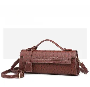 Macro view of brown ostrich pattern leather bag with metallic hardware and top handle