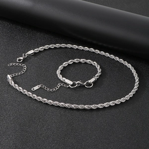 Polished stainless steel twist rope necklace and bracelet set on dark textured surface