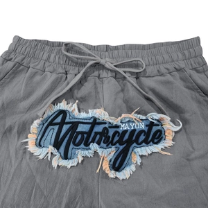 Nahaufnahme vom elastischen Kordelzugbund mit Vintage-Stickerei auf grauer Leinenhose