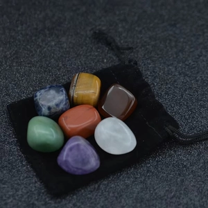 Detailed macro view of 7 assorted chakra healing stones with a black velvet storage pouch