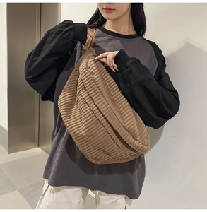 Brown corduroy crossbody bag shown on a female model in a casual indoor setting