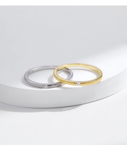 Detail of silver and gold irregular textured cross rings with small square diamonds