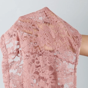 Close-up of pink floral lace fabric showing intricate vine patterns and sheer mesh texture