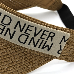 Macro detail of brown straw sun hat with canvas ribbon and black graphic print