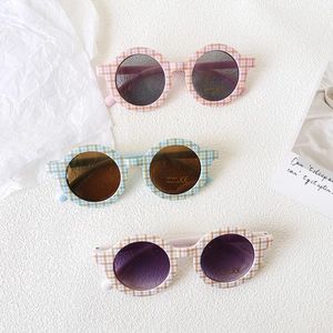 Flat lay of colorful round-frame kids sunglasses with UV400 protection and plaid pattern