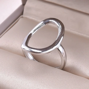 Macro shot of silver polished open ring with an irregular hollow oval design on velvet