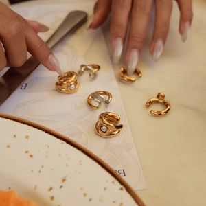 Dettaglio di orecchini a clip in acciaio inossidabile e perle su carta decorativa